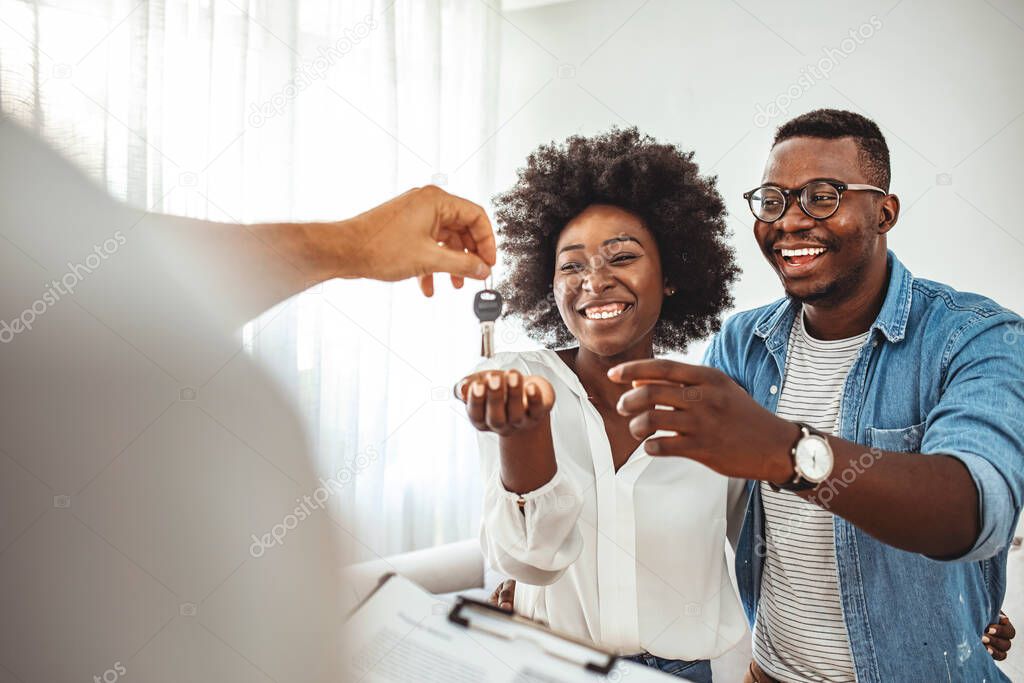Couple Getting Keys From Realtor Of Their New Home. Portrait of financial adviser congratulating to a young couple for buying a new house. African-American  family buy new house.