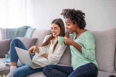 Kadınlar rahat bir dairede dizüstü bilgisayar kullanarak eğleniyorlar. Makyaj dersleri izleyip dışarı çıkmaya hazırlanıyorum. Kadın arkadaşlar evde eğleniyor, dizüstü bilgisayar kullanıyorlar.
