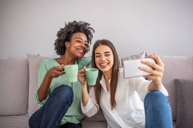Çok güzel bir fotoğraf. Şirin bayan arkadaşları selfie çekiyor. Neşeli, eğlenceli dişli, sıradan kot pantolon ve gömlekler giyiyor.