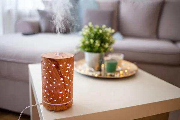 Humidifier on the table in the living room. Ultrasonic technology, increase the humidity in the room, comfortable living conditions. Aroma oil diffuser on white table at home, space for text. Air freshener