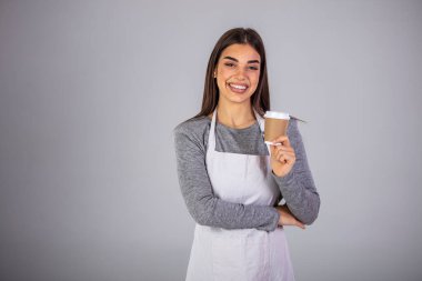 Önlüklü mutlu esmer garson izolasyonda kameranın önünde dikilirken sana sıcak kahve ikram ediyor. Bir garson elinde kağıt bir fincan sıcak kahve tutuyor ve servis ediyor.