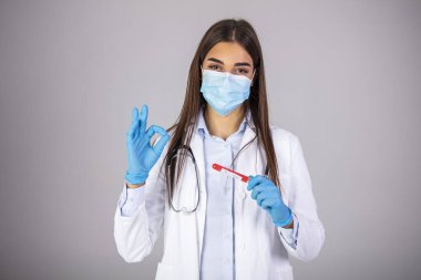 Maskeli bir kadın doktor, üzerinde kan örneği olan bir kovid 19 test tüpü tutuyor. Coronavirus kan testi konsepti. Doktor elinde Coronavirus testi için test tüpündeki kan örneği. 2019-nCoV veya COVID-19 testi için kanla tüp.
