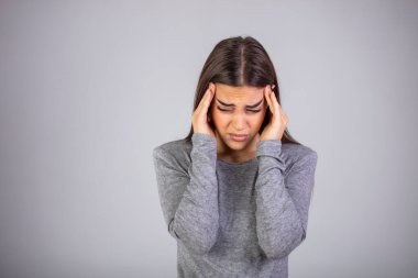 Şakaklarına el ele tutuşan bir kadın korkunç bir baş ağrısı çekiyor. Stüdyo çekimi gri duvarda. Kadının korkunç bir baş ağrısı var, beyaz duvarda izole edilmiş. Stüdyo çekimi