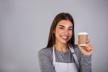 Kapalı fotograf çok güzel bayan garson kafeterya sahibi el ele tutuşmuş kağıt bardak sıcak içecek kafeyi ziyaret et gündelik kazak giy ve önlük gri arka plan