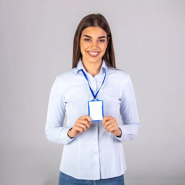 Young smiling woman holding a blank business card. Businesswoman with blank business card. Woman holding, showing corporate id pass, name tag on white background