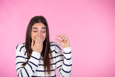 Bu çok küçük. Parmaklarıyla küçük bedenini gösteren güzel bir genç kadının renkli stüdyo portresi. Pembe arka plan. Biraz daha! Çekici genç bir kadının izole edilmiş bir fotoğrafı. Elleriyle boyunu gösteriyor. 