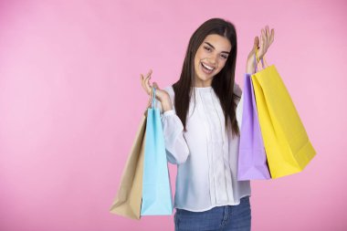 Neşeli genç bir kadın, içinde alışveriş torbaları olan çantalar taşıyor. Renkli alışveriş torbalarıyla neşeli moda kızı. Hediyelerle dolu çantalar. Kafkasyalı mutlu bir kadın. Alışveriş, satış, Kara Cuma konsepti..