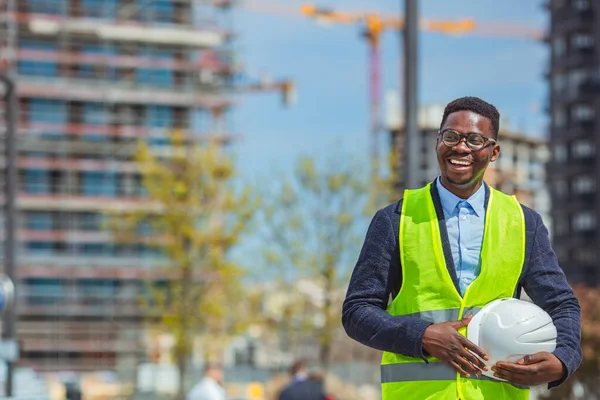 Architect worker holding white helmet a for workers security control at city site. Construction worker holding white hemlet. Engineering Construction holding helmet blueprint at Construction background