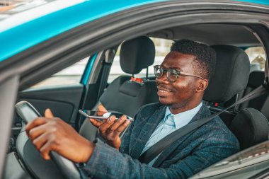 Araba kullanarak arıyorum. Araba kullanırken telefonu kullanması tehlikeli. Yakışıklı genç bir iş adamının arabasında cep telefonuyla konuşmasına yakın çekim. İş adamı araba kullanırken telefonda konuşuyor.