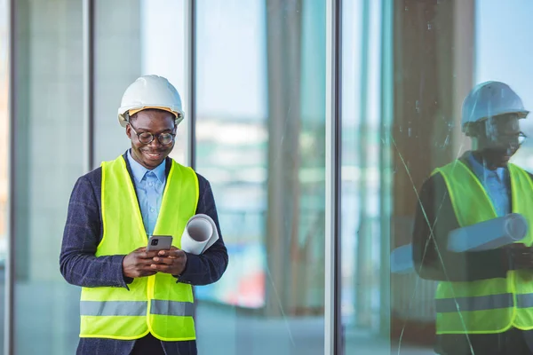 Engineers man working on tablet plan building construction in city. Portrait of bearded architect in formal wear using on the phone and holding project and tablet while standing on construction site.