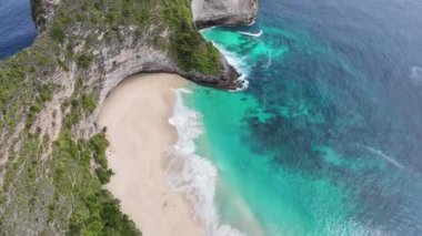 Nusa Penida, Bali 'deki Kelingking Sahili' nin üzerinde uçan FPV insansız hava aracı görüntüleri turkuaz suyu ve beyaz kumları gösteriyor..