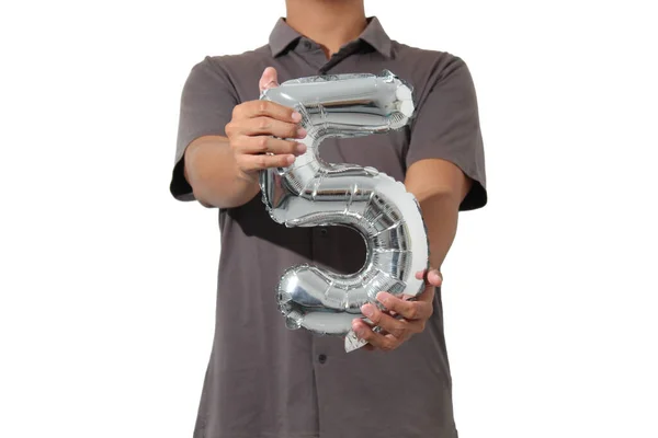 Beyaz arka planda izole edilmiş gümüş renkli 5 numaralı balonu tutan kısa kollu bir adam.