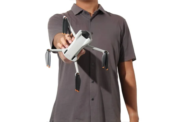 Beyaz arka planda izole edilmiş bir dronu gösteren günlük kısa kollu bir gömlek giyen bir kişi.