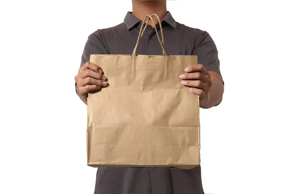 Kısa kollu gömlekli bir adam kahverengi bir kesekağıdı tutuyor ve iki eli de beyaz arka planda.