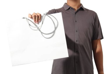 Bir eli beyaz arka planda izole edilmiş beyaz bir kese kağıdı tutan kısa kollu bir adam.