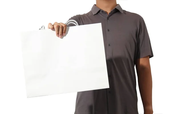 Bir eli beyaz arka planda, büyük beyaz bir kese kağıdı tutan sıradan kısa kollu bir adam.