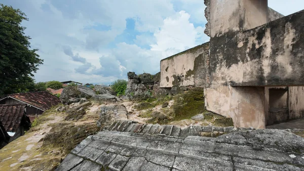 Terk edilmiş beton kalıntılar yıpranmış duvarlar ve bulutlu bir gökyüzünün altında yosun kaplı taşlar.