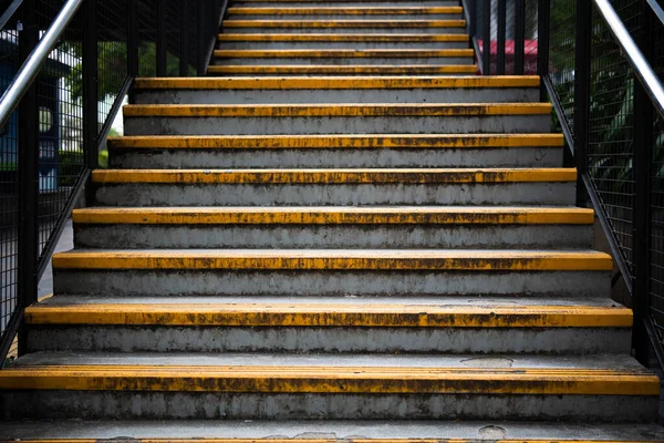 Manzarada sarı güvenlik çizgileri olan yaya köprüsü merdivenleri.