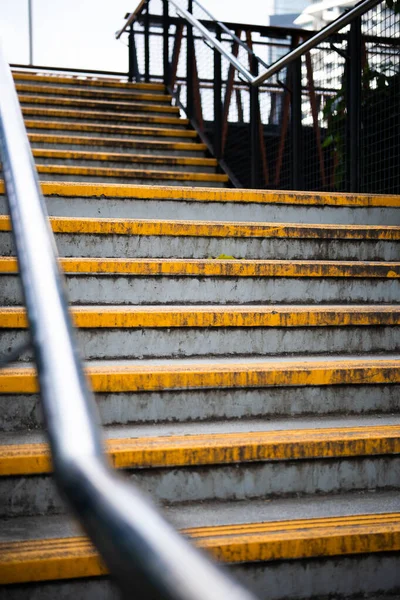 Resimde sarı çizgili yaya köprüsü merdivenleri.