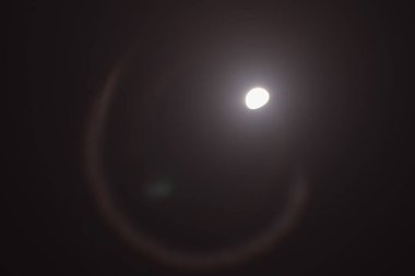 Full Moon Glowing Through Dramatic Dark Clouds in Deep Blue Night Sky A mesmerizing view of a bright full moon partially obscured by wispy clouds in a midnight blue sky. Atmospheric night landscape with soft moonlight illumination