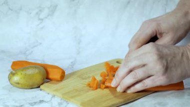 Ahşap kesme tahtasında haşlanmış havuç dilimleyen kadın elleri keskin bir mutfak bıçağıyla ahşap bir tahtanın üzerinde kaynamış turuncu bir havucu dilimlemek için yakın plan kadın eli.