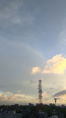 Şehrin üzerinde bulutlar ve antenlerle altın saat gökyüzü sakin bir manzara yaratıyor.