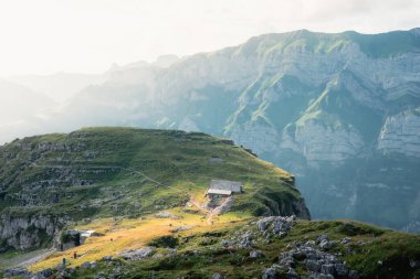 Appenzell 'deki yeşil bir alp sırtında küçük bir kulübe İsviçre Alp Dağları' nın tepelerine tepeden bakıyor..