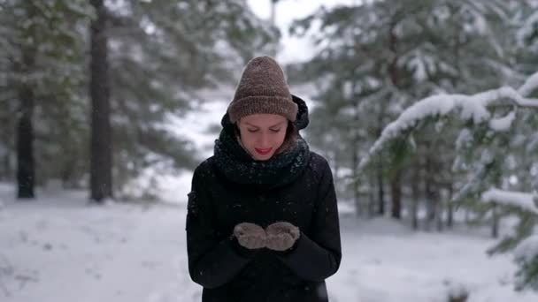 Femeia atractivă în pădurea de iarnă prinde fulgi de zăpadă și se bucură cu adevărat de ea . — Videoclip de stoc