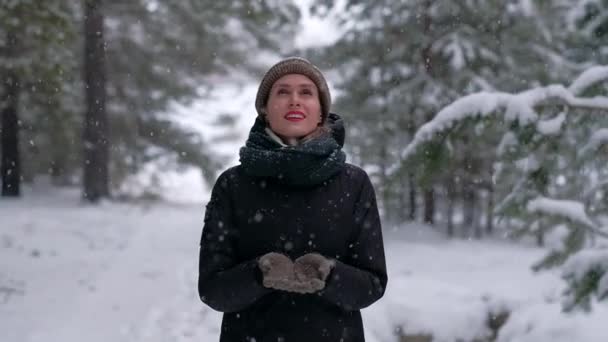 Attractive female in winter forest catches snowflakes and is really enjoying it. — Stock Video