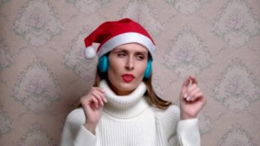 Noel şapkalı ve kulaklıklı genç pozitif dansçı kadın..