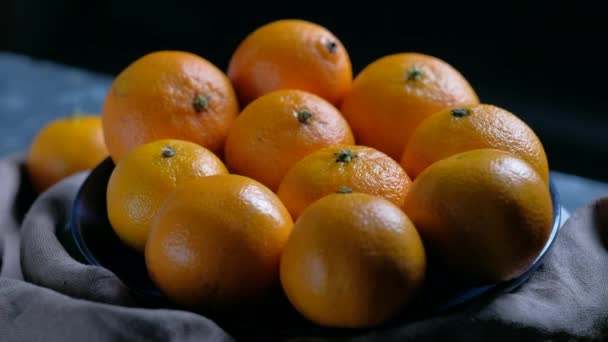 Купка нечистого круглого стиглого апельсинового мандарина в тарілці . — стокове відео