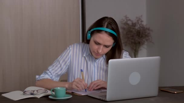 Νεαρή μαθήτρια με ακουστικά που σπουδάζει στο σπίτι, online εκπαίδευση. — Αρχείο Βίντεο