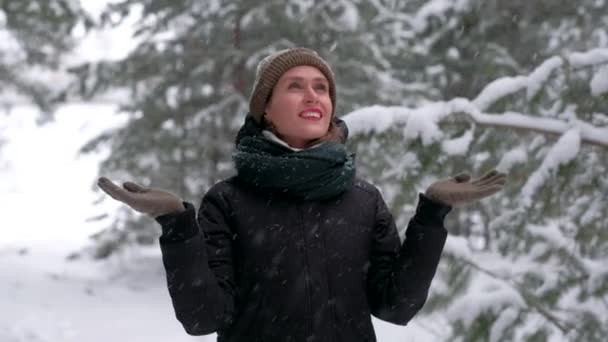 Fêmea atraente na floresta de inverno pega flocos de neve e está realmente gostando. — Vídeo de Stock