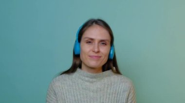 Güzel bir kız müzik dinler ve renkli kulaklıklarla başını sallar..