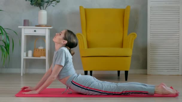 Morena hembra hace ejercicios de yoga para estirar los músculos de la espalda en la mañana en casa. — Vídeo de stock