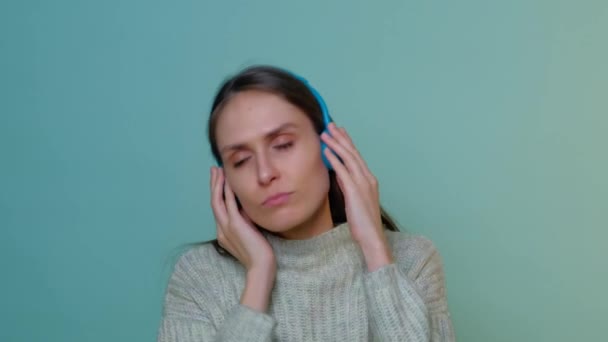 Una hermosa chica escucha música y sacude la cabeza con auriculares de colores. — Vídeos de Stock