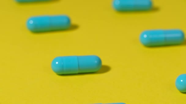 Pílulas azuis em um fundo amarelo. — Vídeo de Stock