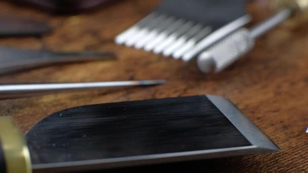 Primer plano de diferentes herramientas de curtidor que yacen sobre una mesa de madera. — Vídeos de Stock
