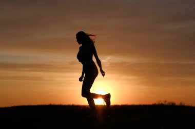 Günbatımı arka planında kadın silueti sıçraması.