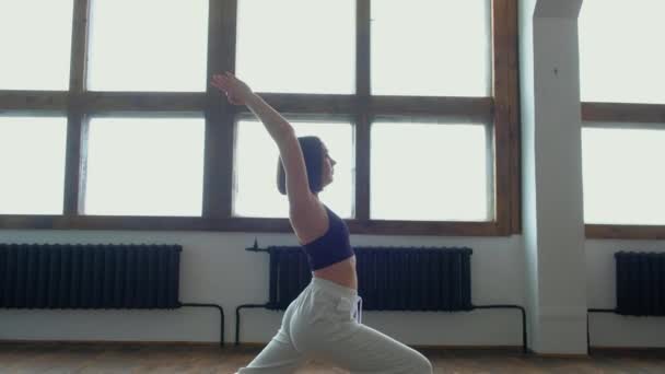 Vrouw in haar woonkamer in krijger yoga pose. — Stockvideo