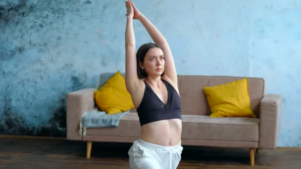 身着战士瑜伽的女人在客厅里摆姿势. — 图库视频影像