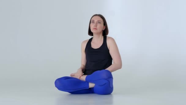 Молодая женщина в спортивной одежде практикует йогу. — стоковое видео