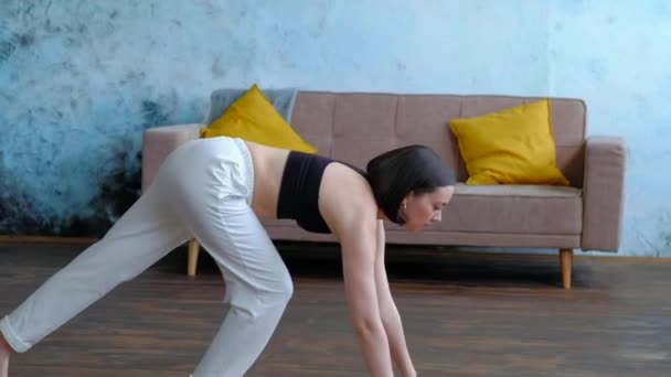 Carino donna bruna fa esercizi di yoga a casa moderna su sfondo divano. — Video Stock