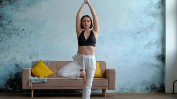 Glückliche Frau praktiziert Yoga, steht in Vrksasana, Baumstellung — Stockvideo