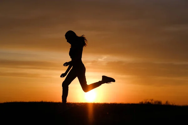 Feminino silhueta salto ao pôr do sol fundo. — Fotografia de Stock