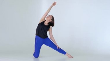 Spor kıyafetleriyle evde yoga pozu veren formda bir kadın..