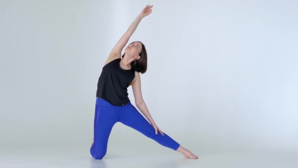 Fit Frau in Sportbekleidung übt Yoga-Tor-Pose zu Hause. — Stockvideo