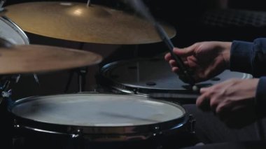 Tanınmayan bir adam oturur ve davul çalar.