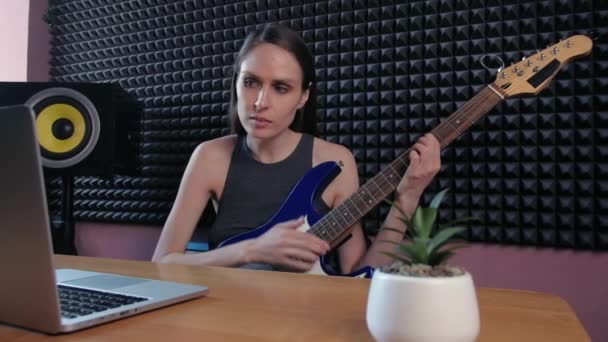 Adolescente aprendizaje femenino tocar la guitarra en casa utilizando lecciones en línea. Hobby educación musical remota electro guitarra. — Vídeo de stock