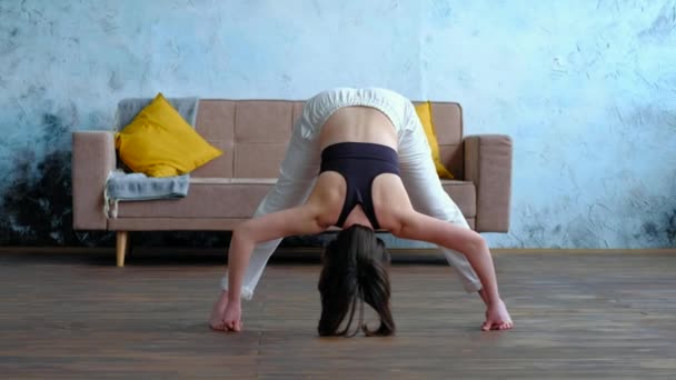 Master Yoga kvinna gör poser i hemmet, Prasarita Padottanasana. — Stockvideo